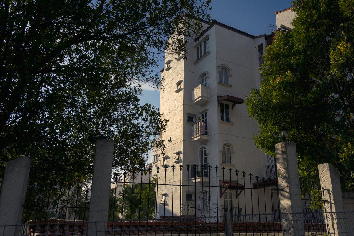 An apartment building stands behind trees and a fence in Kuala Lumpur.